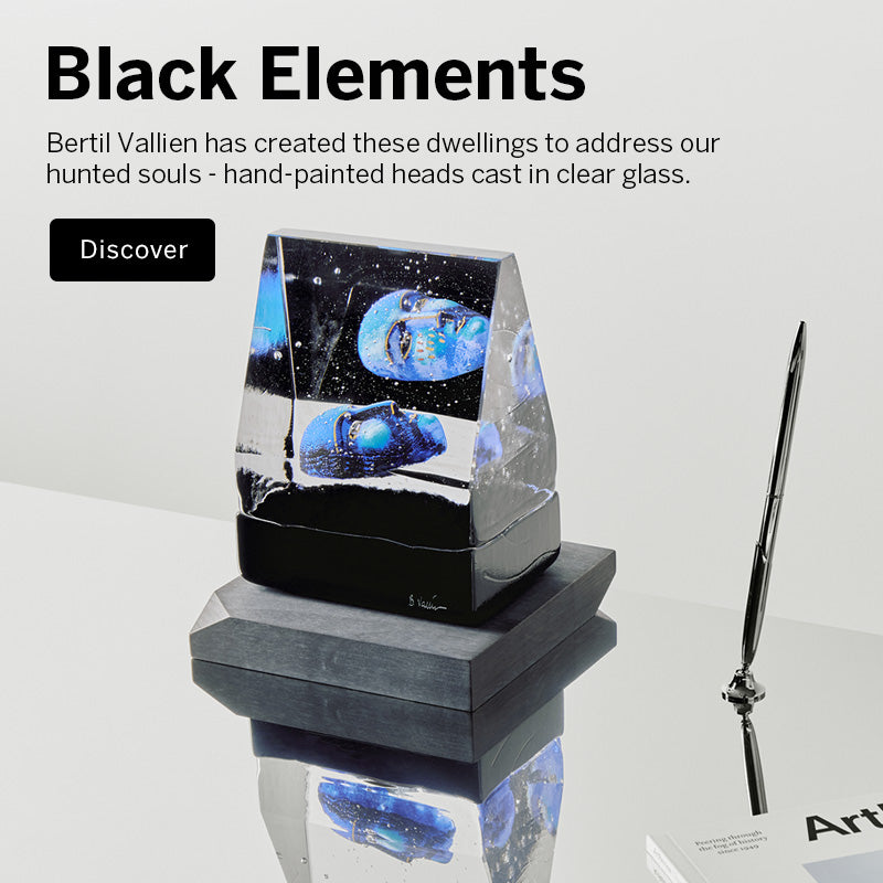 Black glass sculpture with hand-painted heads on a white background, featuring text about Bertil Vallien's creations.