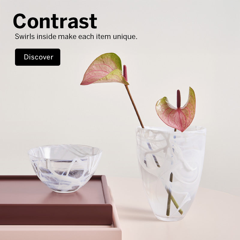 Mobile version of a styled interior scene with crystal Contrast Collection white/White vase and bowl on a dark brown tray and a clear glass vase holding pinkish-red anthurium stems, set against a warm off-white background with the text 'Contrast' Swirls inside make each item unique in the upper left.