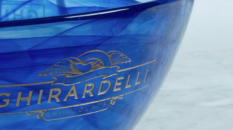 Blue Contrast Bowl with engraved Ghirardelli logo on a white background demonstrating engraving services.