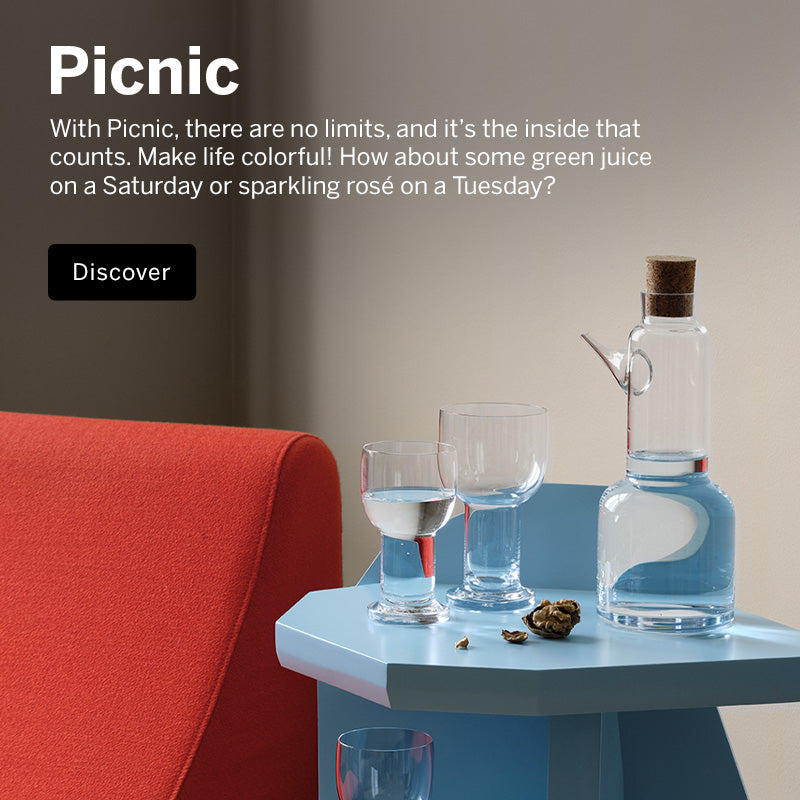 Mobile version of Picnic collection crystal carafe, and glasses on light blue side table with walnuts next to a contemporary orange hair in corner room setting.