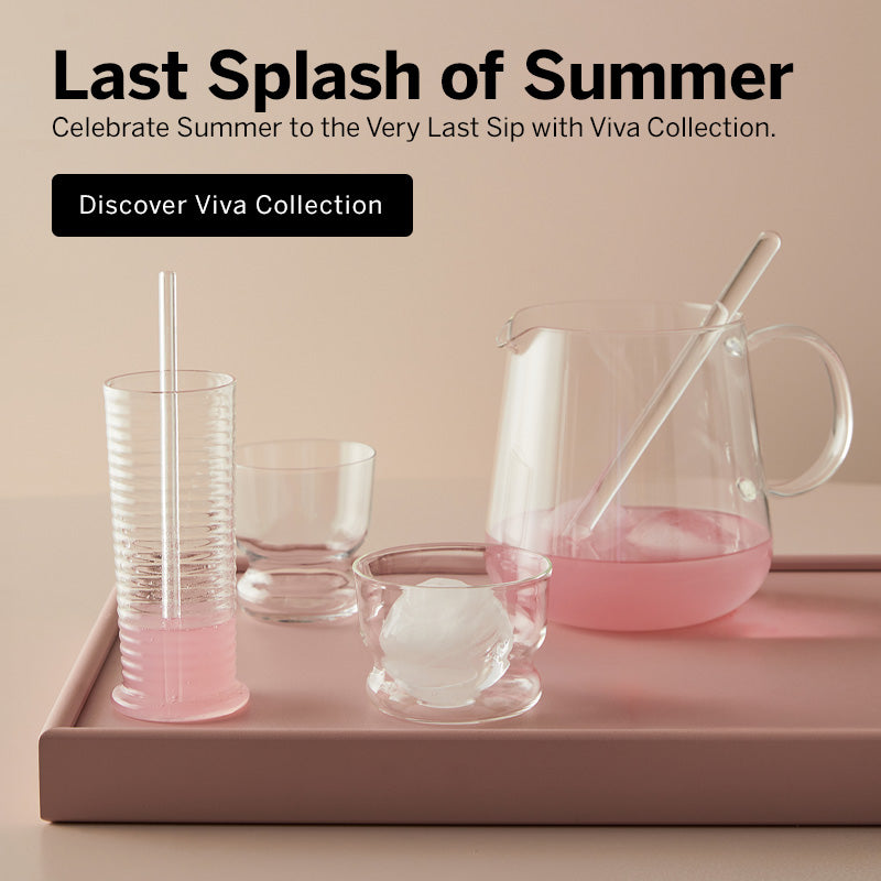 Mobile version of Viva collection crystal pitcher filled with pink liquid and a crystal mixing stick in it sitting on a pink tray beside a ribbed Viva tumbler glass with a crystal straw, a small clear Viva DOF glass, and a round ice in the glass, against a warm beige background with promotional text "Last Splash of Summer" at the top.
